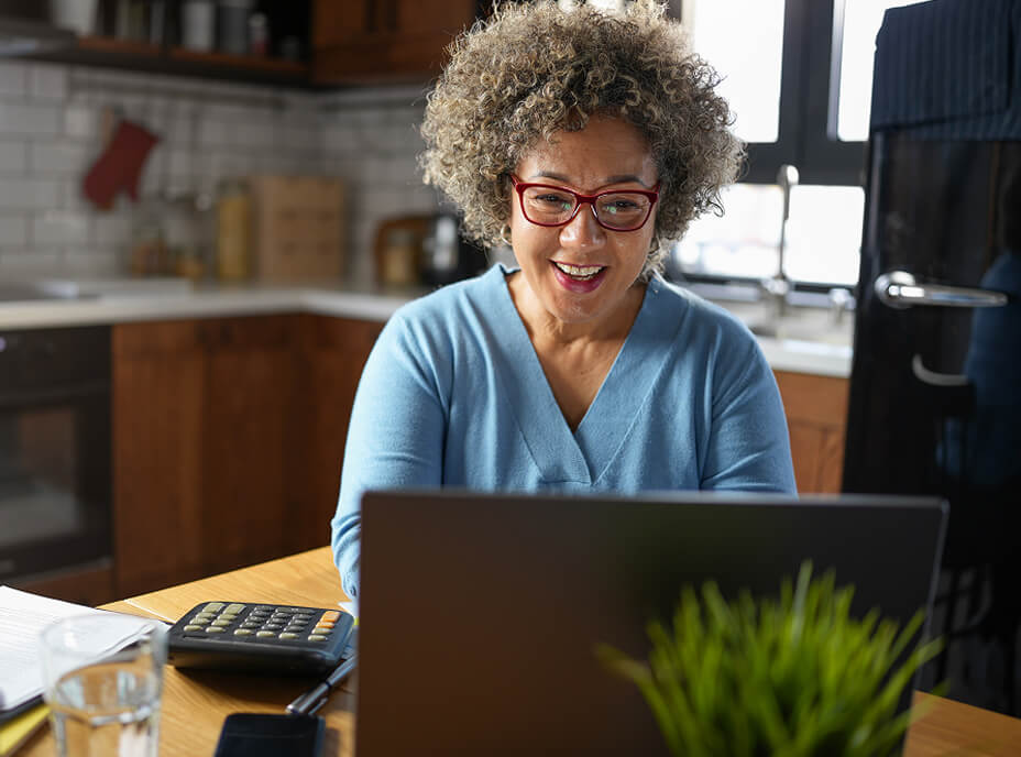 Woman using a laptop at her kitchen table