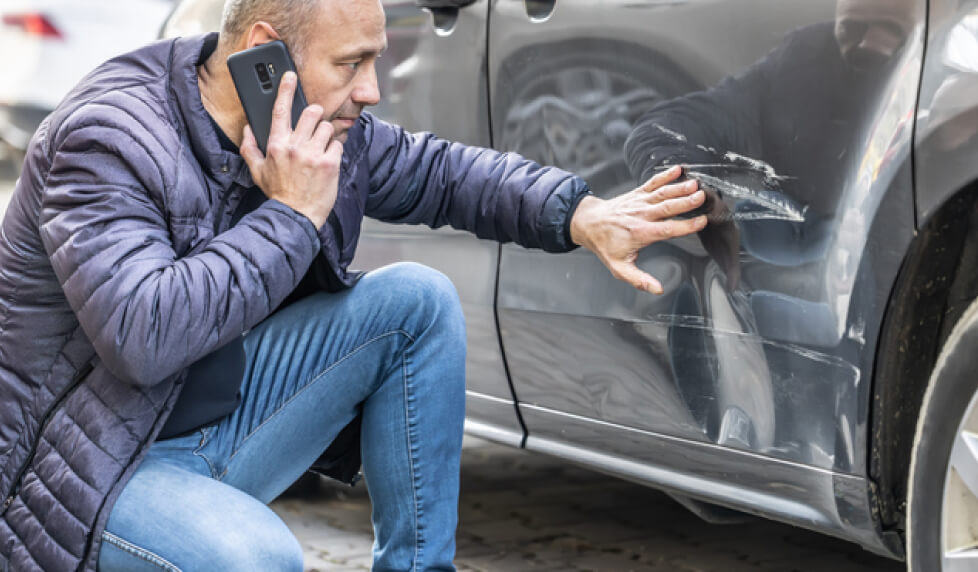 man inspecting damage to car