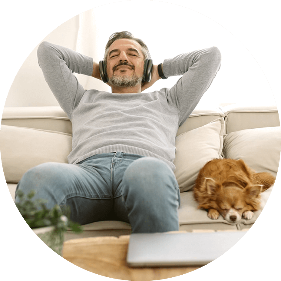man listening to music with dog on couch