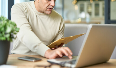 Man looking at envelope and laptop