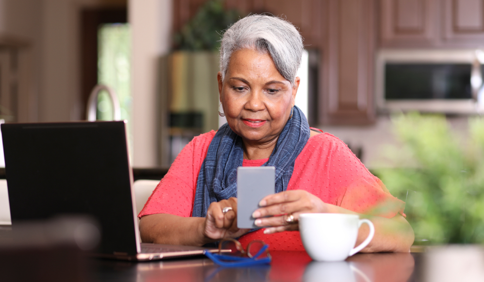 Lady in Kitchen looking at phone and computer