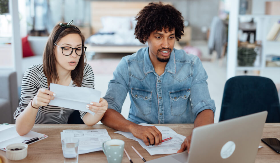 young couple with paperwork on computer