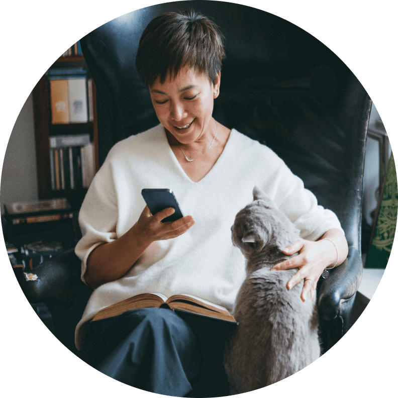 woman rubbing cat on cell phone